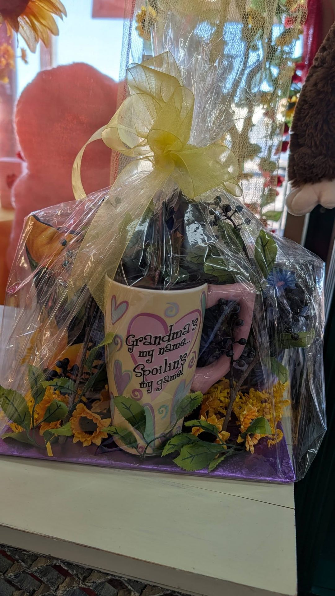 Cellophane-wrapped grandma gift basket with mug and sunflowers.